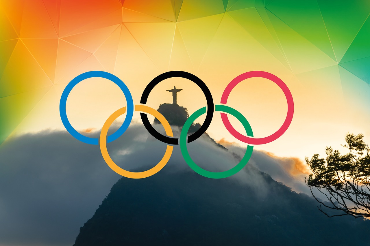 Graphic showing the iconic Rio Cristo Redentor statue at the top of Mount Corcovado in Rio, with the flag colours behind and the Olympic rings superimposed on top.